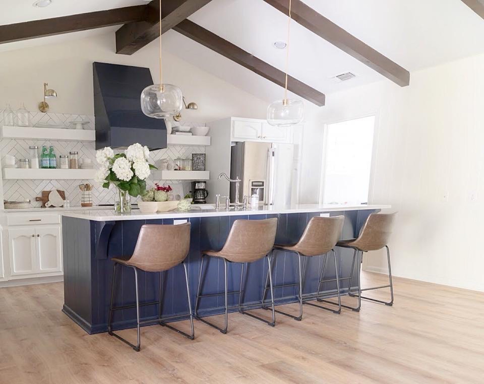 Vaulted kitchen with wood beams, navy island and leather stools