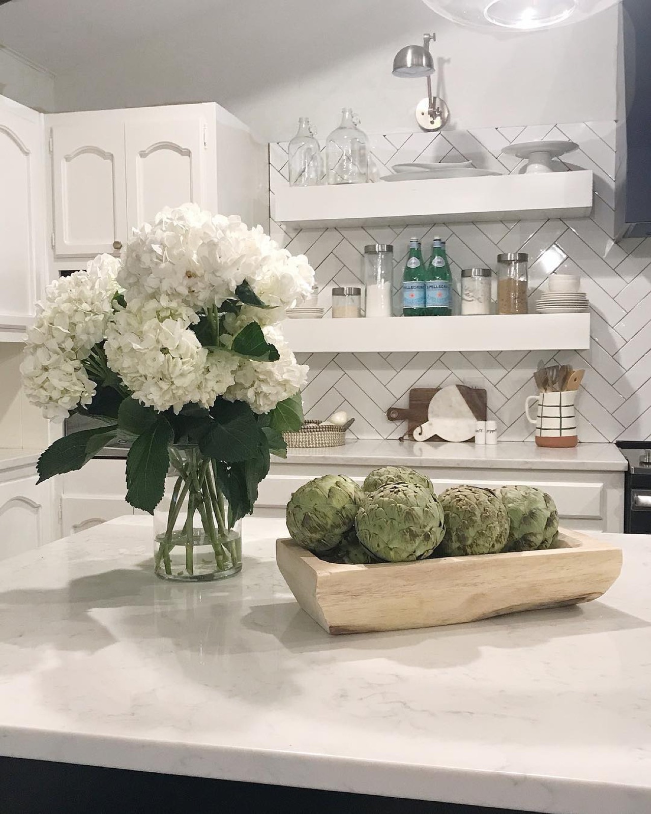 White kitchen with open shelving and fresh hydrangeas