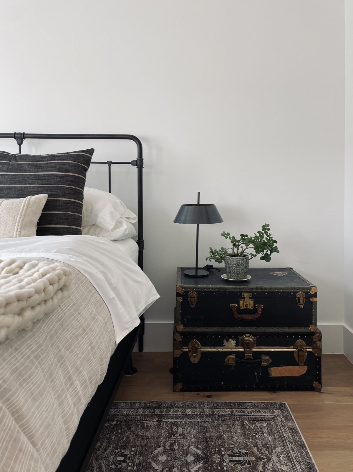 Guest bedroom with black iron bed and vintage trunk