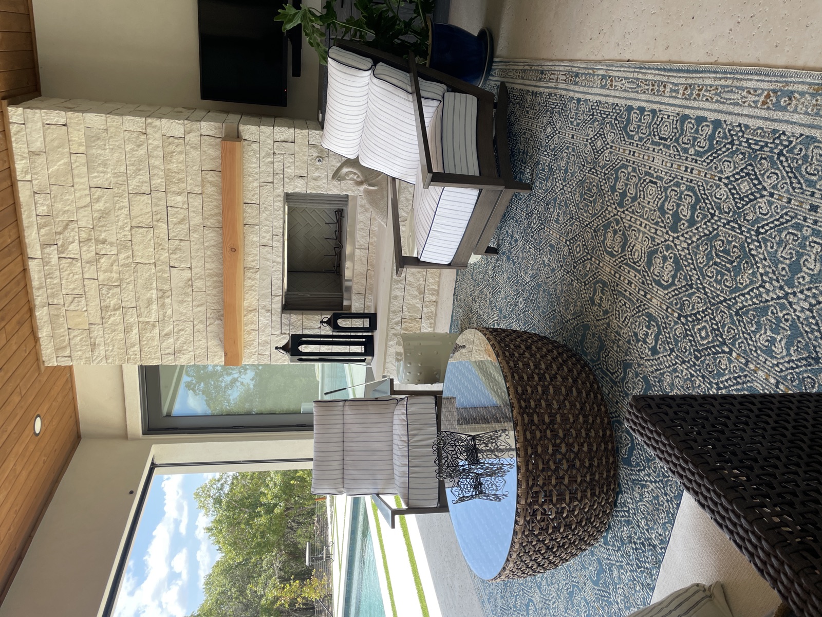 Covered patio with stone fireplace and woven furniture