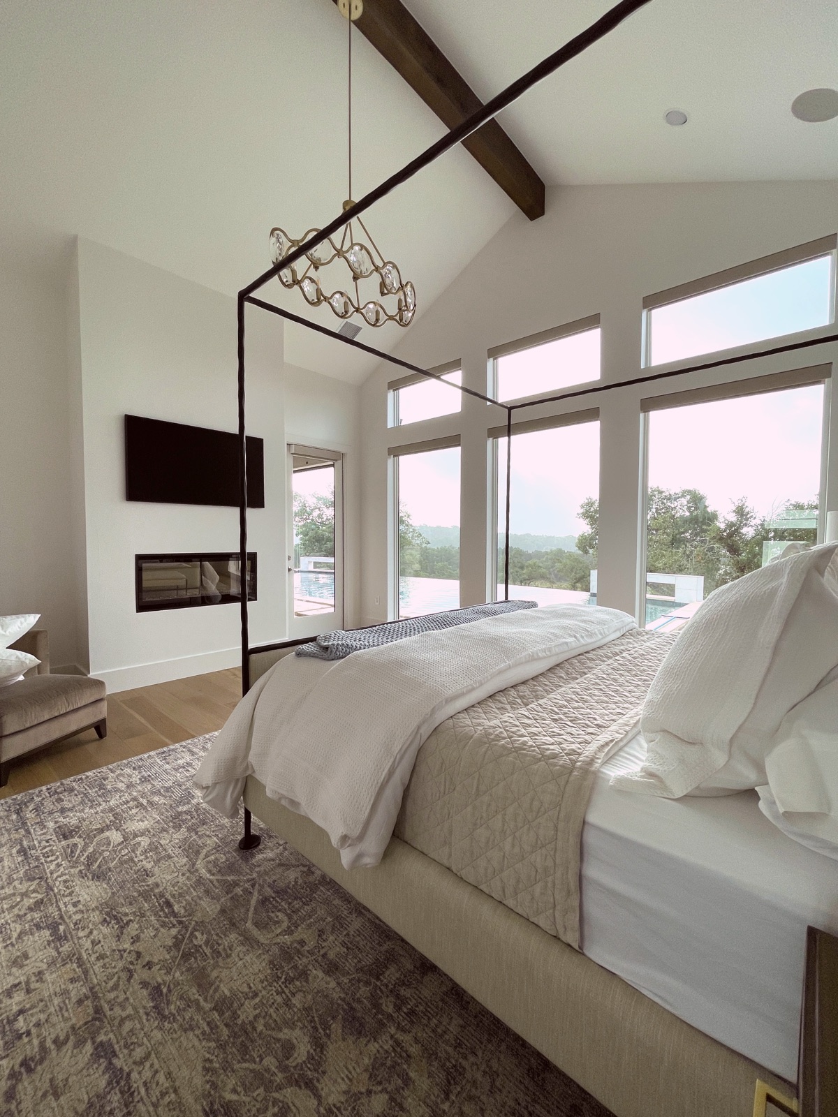 Primary suite with black canopy bed and hill-country views
