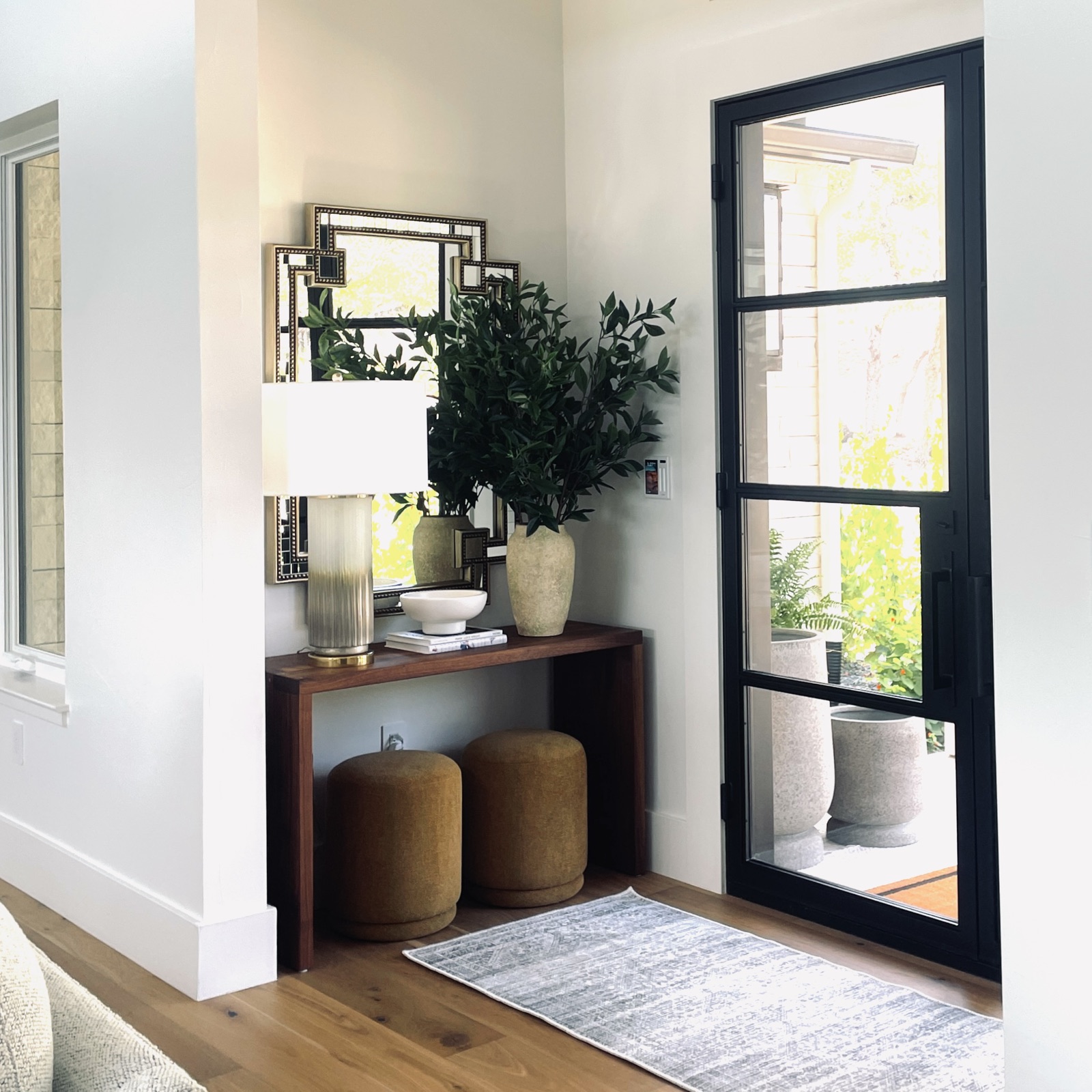 Entry console with black-framed mirror and greenery