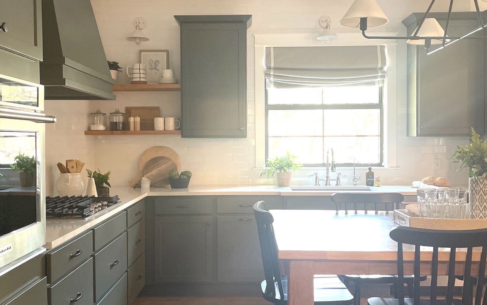 Sage-green kitchen with picture window and butcher-block accents