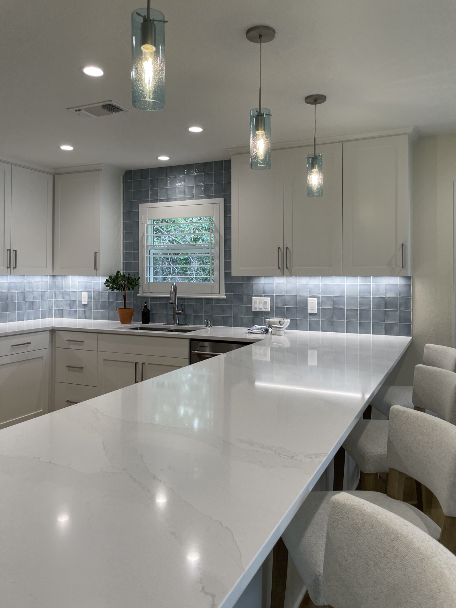 Kitchen with glass tile backsplash and pendant lighting